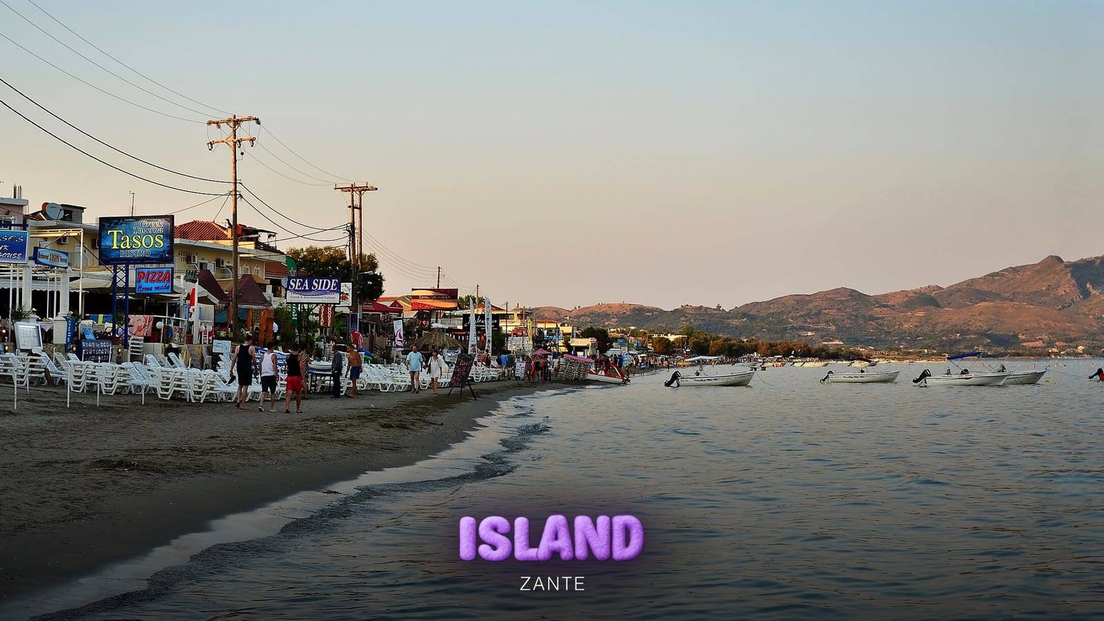 Laganas beachfront at dusk, with the beach bars, small boats and the Keri hills in the distance